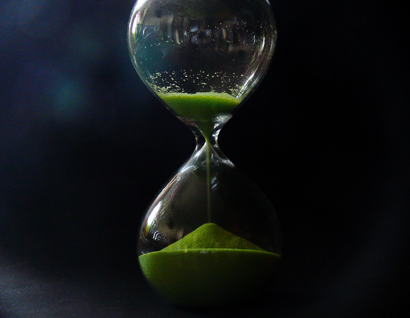 Large canva   hourglass with green sand on black background